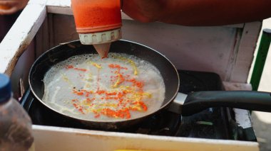 Bir sokak satıcısının arabasında tavaya aromalı omlet serpiştirilmiş.