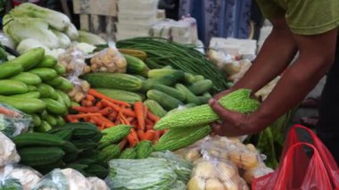 Müşteriler bir tezgahta sergilenen taze sebzeleri seçip geleneksel bir pazarda çeşitli sebzeler satıyorlar. Ağır çekim video çekimi