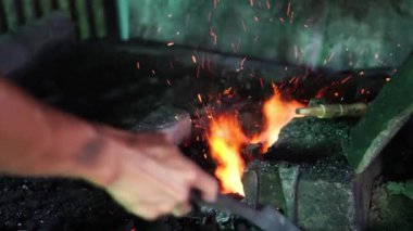 Geleneksel bir demircinin şöminesi yavaş çekimde işçilerin odun kömürü kullanarak elle yakılıyor.