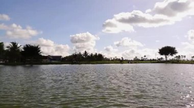 Sıcak bulutlu bir günde, üzerinde küçük dalgalar ve küçük kuşlar uçuşan bir su deposunun üzerinde.