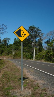 Dağ yollarında sarı heyelan riski işaretleri var. Tepe arazisinde seyahat etmenin tehlikelerini vurguluyorlar. Görsel olarak çok çekici bir kompozisyon yaratıyorlar..