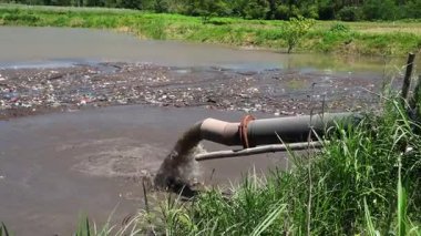 Kirli göletler bulanık su ve plastik atıklarla dolu kontrolsüz endüstriyel atık imhasının sonuçlarını inceliyor. Borulardan akan su ve biyolojik olarak çözülemeyen maddelerin birikmesi çevre üzerinde olumsuz etkiler yaratıyor..