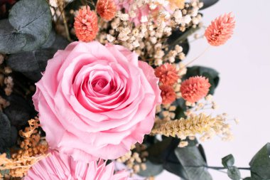 Detalle de un hermoso ramo de rosas rosadas, paniculata, okalipto y trigo en un jarrn sobre la mesa