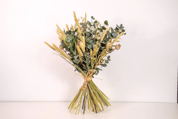 Bouquet of dried flowers in vase on white background.