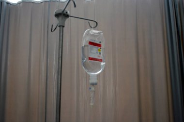 Demir bir direğe asılı kırmızı etiketli bir infüzyon şişesi