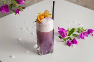 Mor Yağmurlu Parıltı Kokteyli beyaz bir masanın üzerinde Bektaşi üzümü ile süslenmiş.