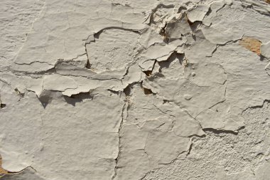 Lekeleri ve çatlakları olan eski beton bir duvar dokusu, beyaz kabuk soyma arka planı.