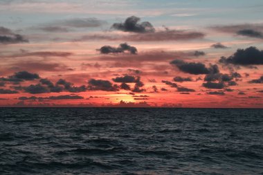 Denizin üzerinde nefes kesen bir gün doğumu gökyüzünü altın ve pembeden renklerle boyar, ruhu büyüleyen büyüleyici bir bulut yaratır.
