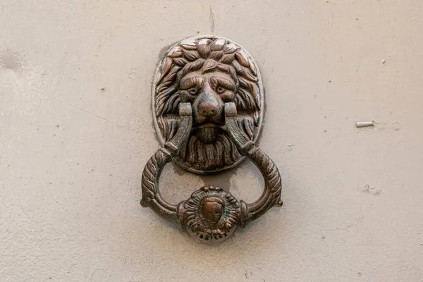 Old bronze door knobs with the shape of a lion\'s head on red door
