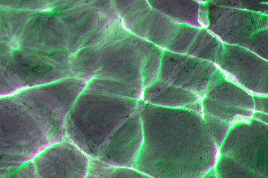 Suyun yüzeyinde canlı güneş ışığı bir çeşmede dans eder, yaşlanmış taş zeminde renkli ve soyut bir doku oluşturur.