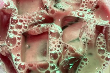 Kabarcıklı renkli sabunlu sıvı. Yakın çekim, şeffaf buz küpleri ve kabarcıklarla bulutlu su dokusu.