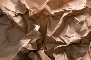 Geri dönüşümün özünü sembolize eden buruşuk bir el işi kağıdı arka planı - atıkların yeniden kullanılması ve azaltılması, sürdürülebilirliğin doku ve karakter ile harmanlanması, çevre dostu bir hatırlatma.