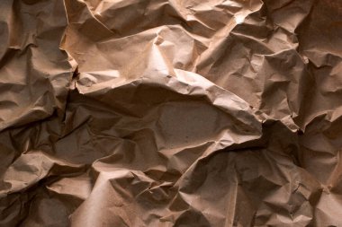 Geri dönüşümün özünü sembolize eden buruşuk bir el işi kağıdı arka planı - atıkların yeniden kullanılması ve azaltılması, sürdürülebilirliğin doku ve karakter ile harmanlanması, çevre dostu bir hatırlatma.