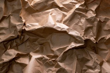 Geri dönüşümün özünü sembolize eden buruşuk bir el işi kağıdı arka planı - atıkların yeniden kullanılması ve azaltılması, sürdürülebilirliğin doku ve karakter ile harmanlanması, çevre dostu bir hatırlatma.