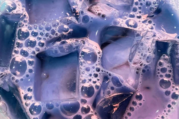 Kabarcıklı renkli sabunlu sıvı. Yakın çekim, şeffaf buz küpleri ve kabarcıklarla bulutlu su dokusu.