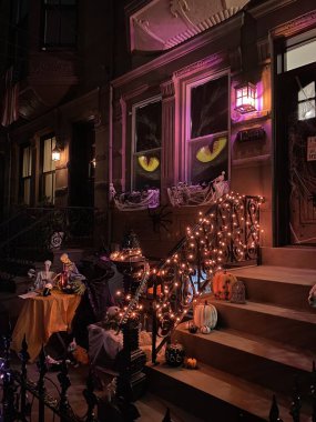 Cadılar Bayramı 'nda evin verandasında turuncu ve mor çelenkler, iskeletler, balkabakları ve hayaletlerle aydınlatılmış cadılar bayramı evi süslemeleri.