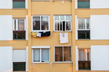 Şehirdeki bir apartmanın balkonunda giysiler kuruyor.