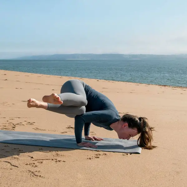 年轻女子在海边练瑜伽 — 图库照片