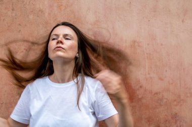 Rüzgarda savrulan uzun saçlı güzel bir kadının portresi.