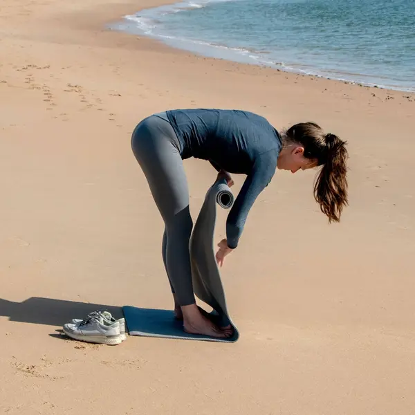 在海滩上做瑜伽运动的年轻女运动员 — 图库照片