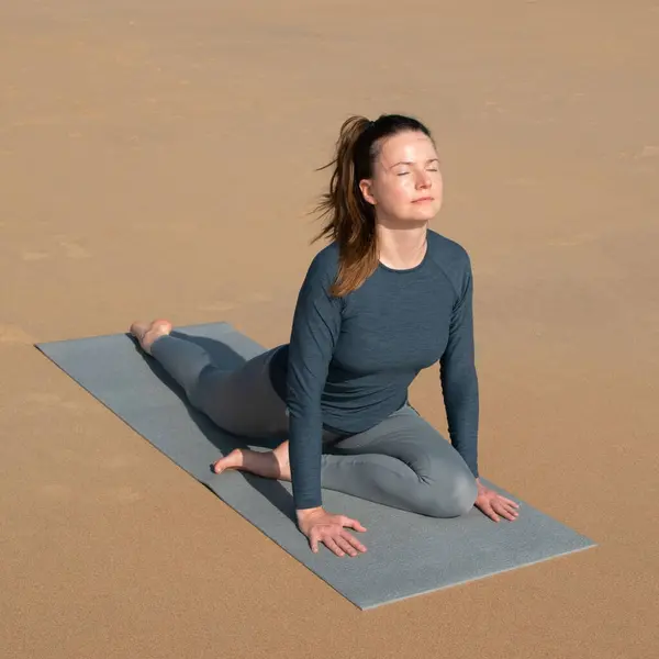 年轻女子在海滩上练习瑜伽 健康生活方式和放松的概念 — 图库照片