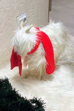 Kırmızı Noel Baba şapkalı beyaz keçi ve beyaz kürklü yeşil çelenk.