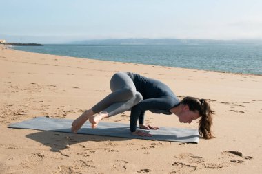 Deniz kenarında yoga yapan genç bir kadın. Sağlıklı yaşam tarzı.