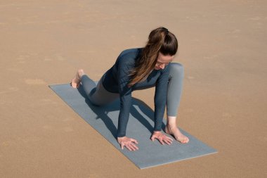 Kumsalda yoga yapan genç bir kadın. Sağlıklı yaşam tarzı ve rahatlama kavramı.