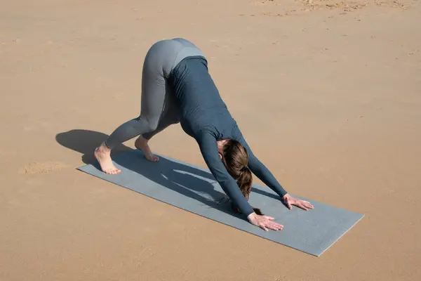 Kumsalda yoga yapan genç bir kadın. Sağlıklı yaşam tarzı ve rahatlama kavramı.