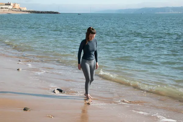 Deniz kıyısında dalgıç kıyafetli genç bir kadın..