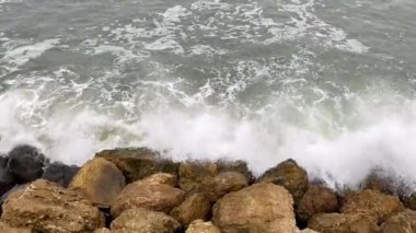 Taş deniz kıyısı, dalgalar taşlara çarpıyor. 