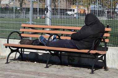 Evsiz bir adam bankta uyuyor.