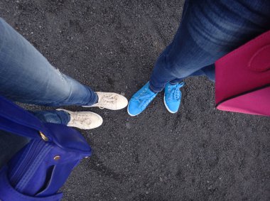 Kot pantolonlu ve parlak spor ayakkabılı kadın bacakları.