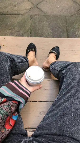 A cup of coffee in hand sitting on the steps in a yard
