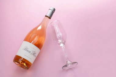 Bilinmeyen bir şişe gül şarabı ve pembe arka planda bir bardak, üst manzara, fotokopi alanı, romantik parti konsepti düzlüğü