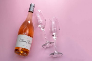 Bir şişe gül şarabı ve pembe arka planda iki bardak, kopyalama alanı
