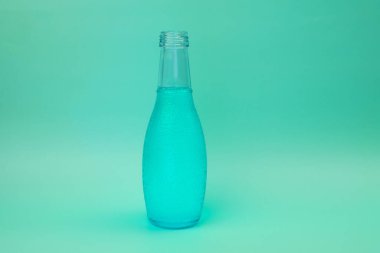 Mavi su şişesi yeşil arka planda izole edilmiş. Metin için alanı kopyala.