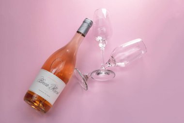Bilinmeyen bir şişe gül şarabı ve pembe arka planda iki bardak, üst manzara, fotokopi alanı, romantik parti konsepti düzlüğü.