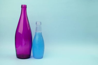 Mor şişe ve mavi şişe mavi arka planda fotokopi alanı ile