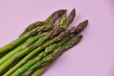 Pembe arka planda taze yeşil kuşkonmaz. Kapat..