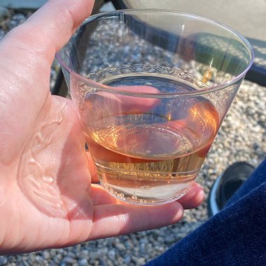 Kumsaldaki bir adamın elinde bir bardak viski.