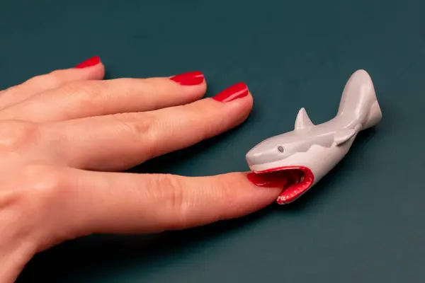 Shark bites a woman\'s hand with red nails, shark attack on human