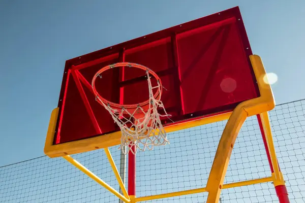 Basketball hoop and net on a basketball court against the blue sky