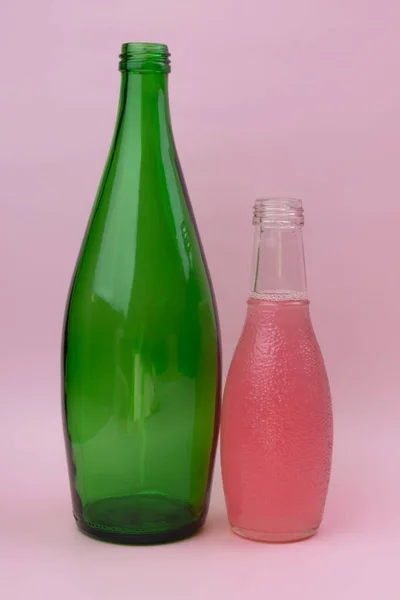 Bottle of pink and green color on a pink background, isolated