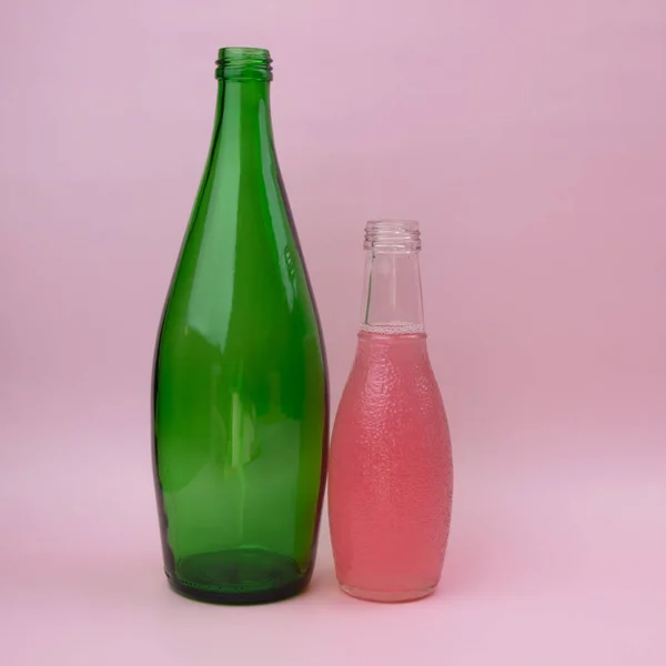 Bottle of pink and green color on pink background with copy space