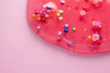 Renkli jel dokusu, baloncuklu temiz cilt kremi ve dekoratif figürler arka plan, şeffaf güzellik serumu, renkli kozmetik ürünler yakın plan.