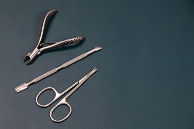 Manikür seti, profesyonel bakım seti, tırnak makası ve tırnak makası, karanlık arka planda tırnaklar ve ayak tırnakları için profesyonel paslanmaz çelik pedikür aletleri.