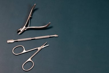 Yeşil arka planda manikür aletleri. Çivi dosyası, makas, cımbız, cımbız..