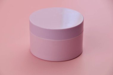 Pembe arka planda pembe bir kutuda kozmetik krem.