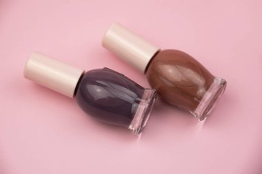 Pembe arka planda küçük cam şişeler, profesyonel manikür konsepti.